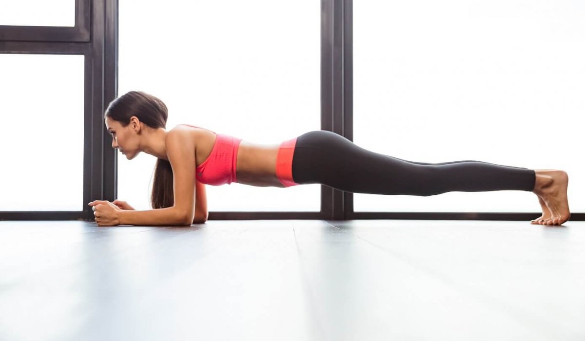 Sports woman doing plank exercise in fitness gym
